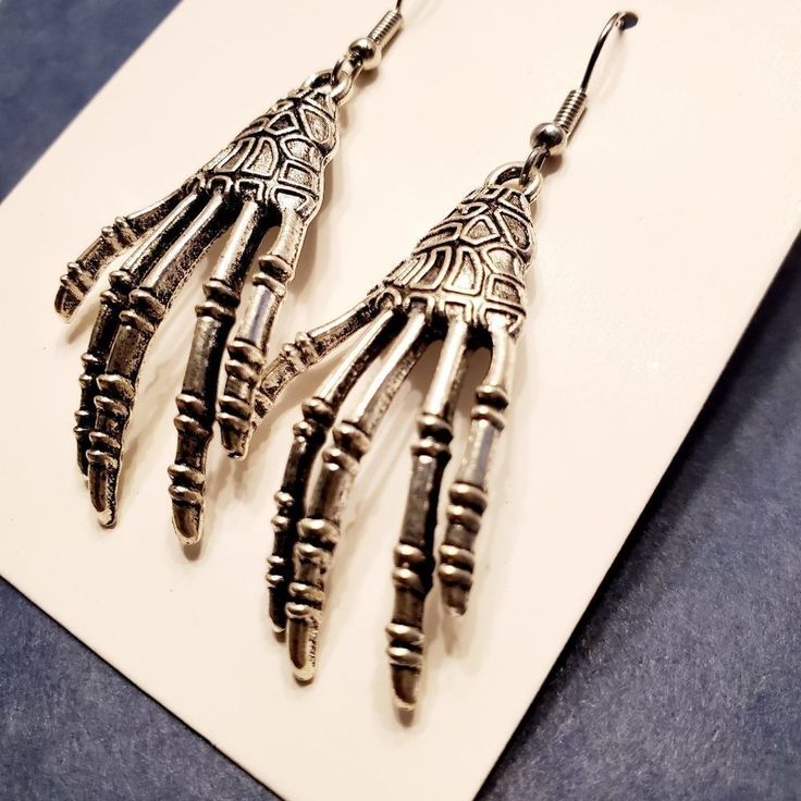 Skeleton Hands Halloween Dangling Fashion Alloy Earrings With Silver Hooks. Length 2" Width 3/4" Nickel-free Punk Halloween Earrings, Nickel-free Punk Earrings For Halloween, Punk Nickel-free Earrings For Halloween, Punk Style Nickel Free Earrings For Halloween, Halloween Skull Jewelry In Bone Color, Edgy Adjustable Earrings For Halloween, Edgy Drop Earrings For Halloween, Halloween Skull Shaped Bone Jewelry, Edgy Halloween Drop Earrings