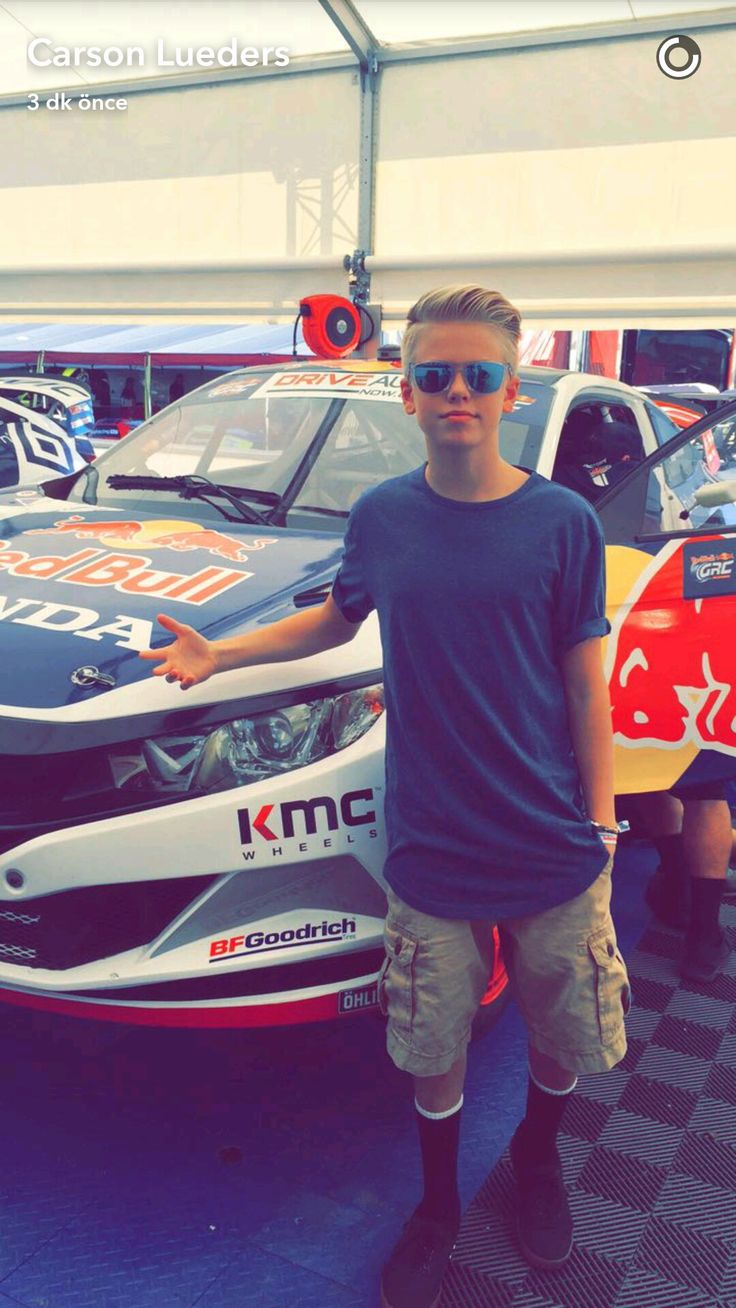 a young man standing next to a racing car