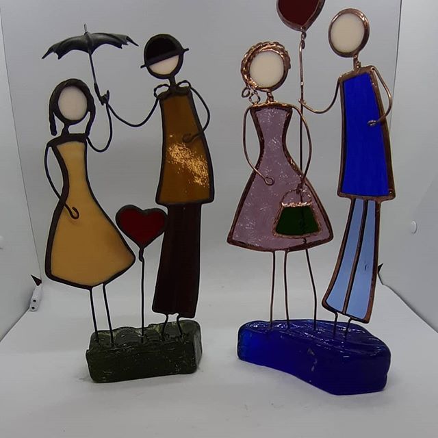 three metal figurines holding hands and standing next to each other with an umbrella