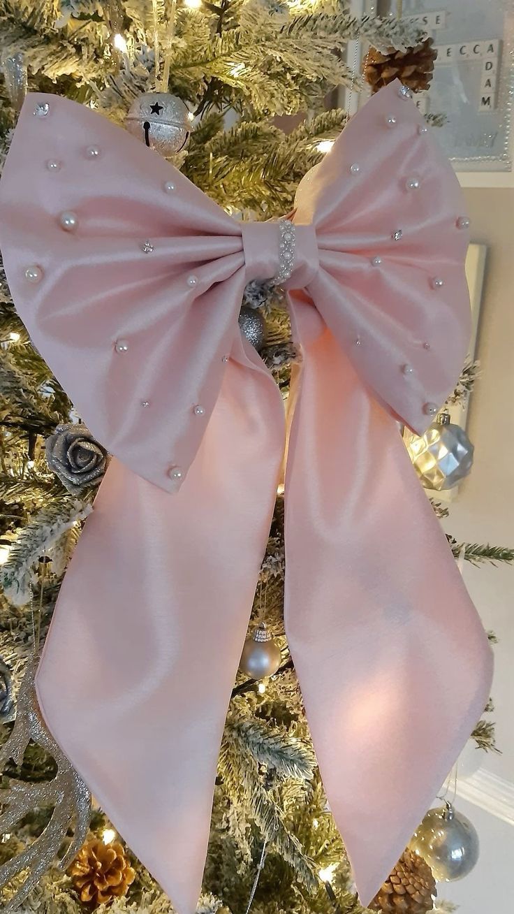 a pink bow on top of a christmas tree