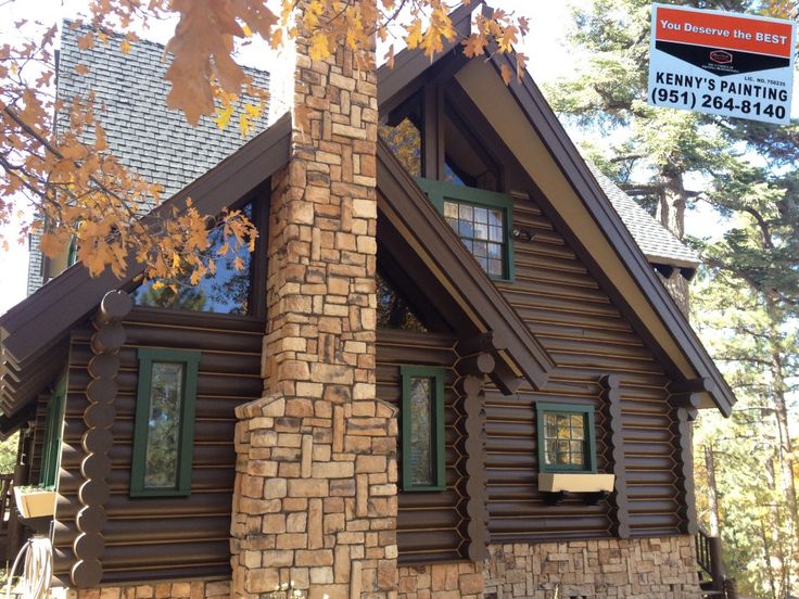 a log cabin with green shutters and windows on the front porch is for sale