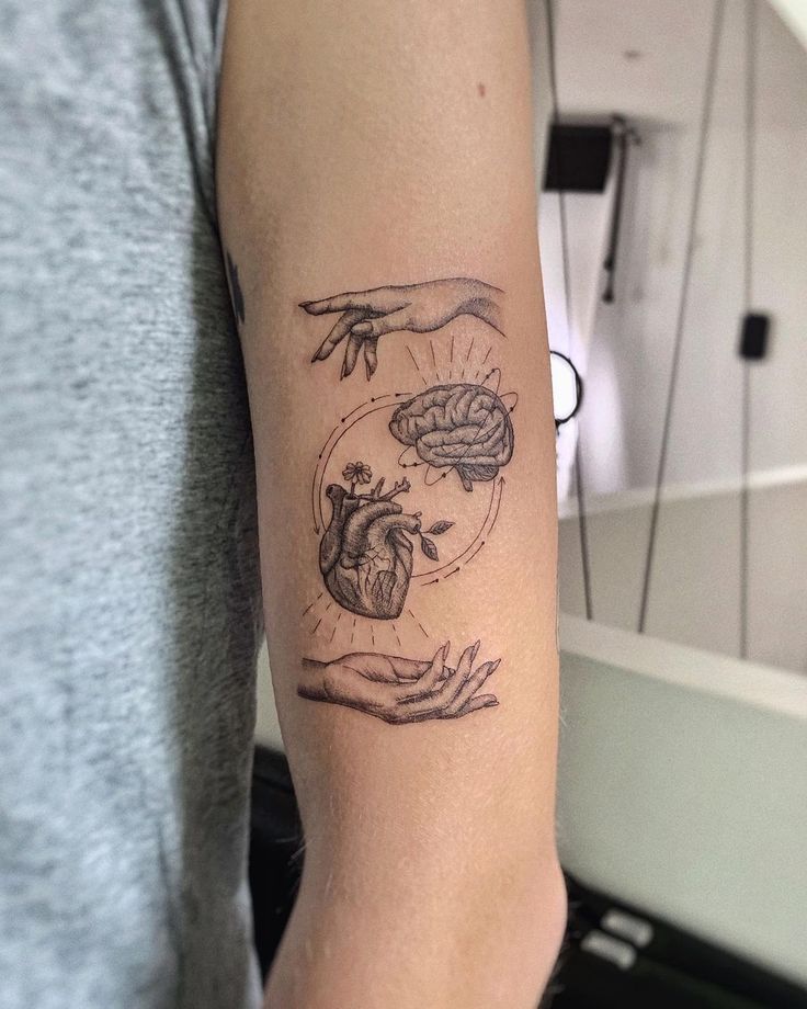 a person with a tattoo on their arm holding a heart and brain in the middle