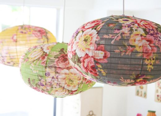 three paper lanterns hanging from the ceiling in front of a window with flowers on them