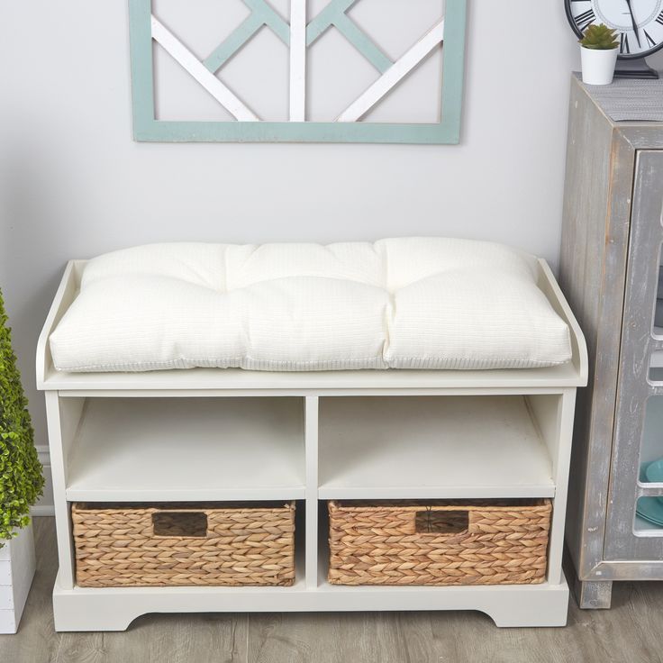 a white bench with two wicker baskets under it and a clock on the wall