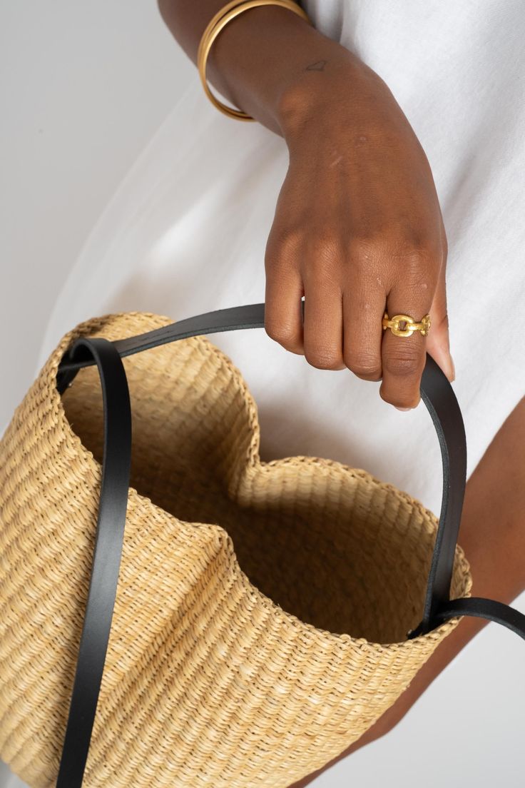 Pinched bucket bag with a short vegetable-tanned leather handle and a long removable strap handwoven in natural straw. Can be worn by hand, on the shoulder or crossbody. Pennisetum purpureum natural fiber and Vegetable-tanned leather Handmade in Ghana and France. Chic Handwoven Natural Fiber Bucket Bag, Natural Jute Top Handle Bucket Bag, Leather Bucket Bag With Bamboo Handle In Natural Color, Natural Leather Bucket Bag With Bamboo Handle, Woven Leather Straw Bag With Top Handle, Chic Handwoven Natural Bucket Bag, Chic Natural Handwoven Bucket Bag, Top Handle Straw Bag With Woven Leather, Leather Straw Basket Bag With Adjustable Strap