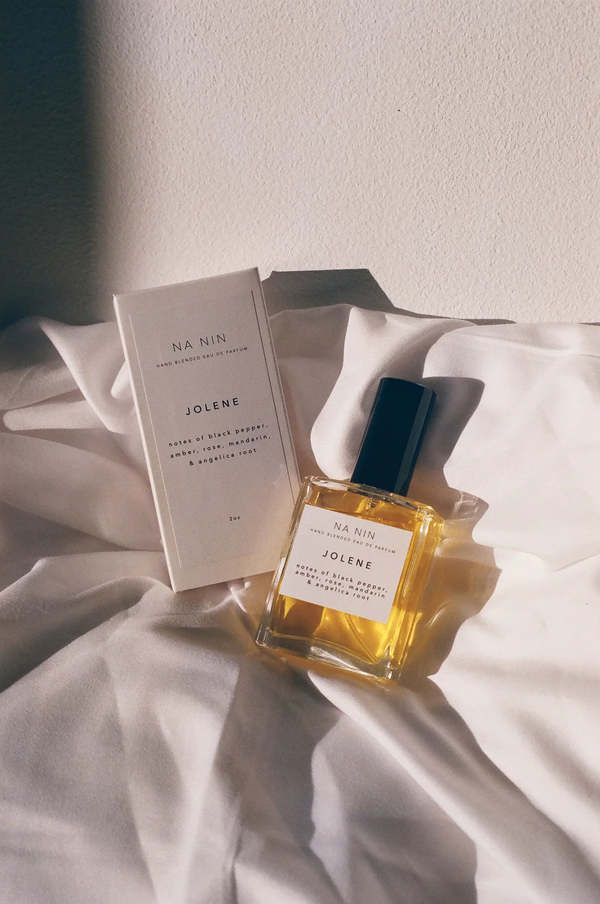 a bottle of cologne sitting on top of a bed next to an open box with the label