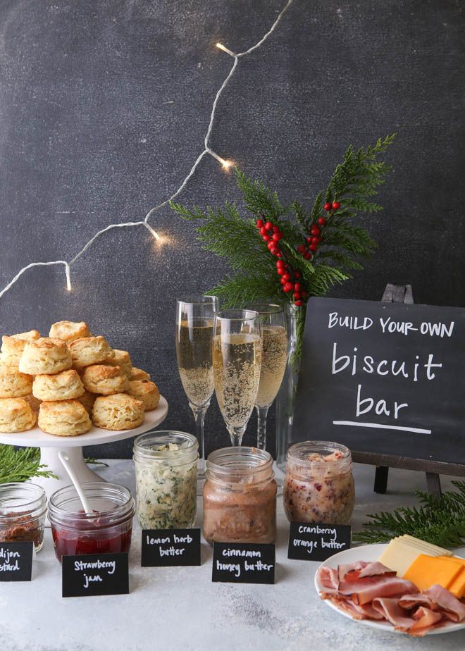 an assortment of food and drinks displayed on a table with chalkboard sign that says build your own biscuit bar