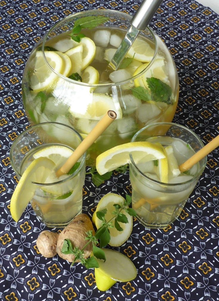 the pitcher is filled with lemonade and ice cubes next to two glasses full of water