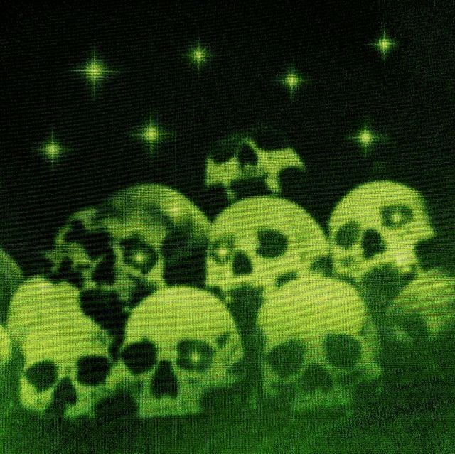 a bunch of skulls that are sitting in the grass with stars on them and one is glowing green