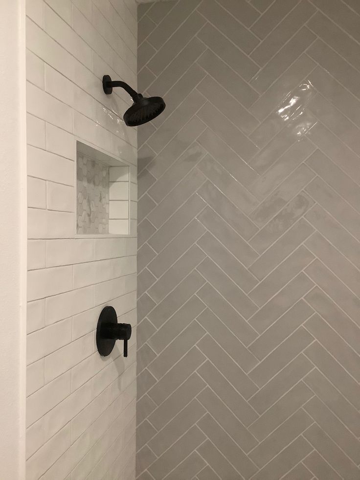 a bathroom with white tile and black faucet shower head next to the bathtub