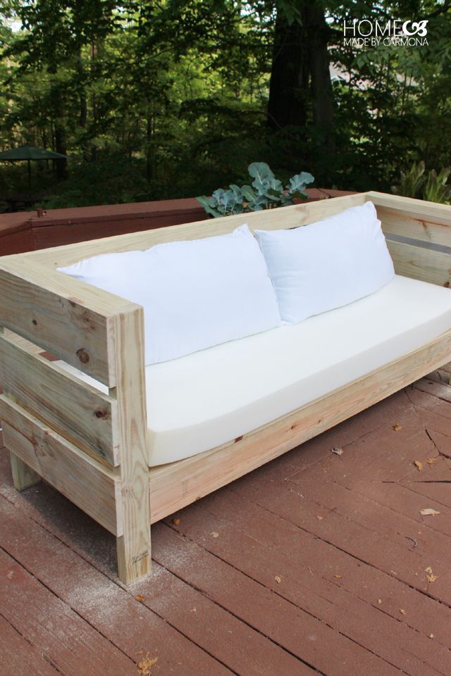 a couch made out of wooden pallets on a deck with yellow poles and pillows