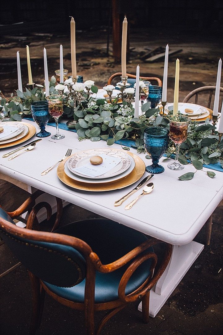 the table is set with candles, plates and greenery for an elegant dinner party