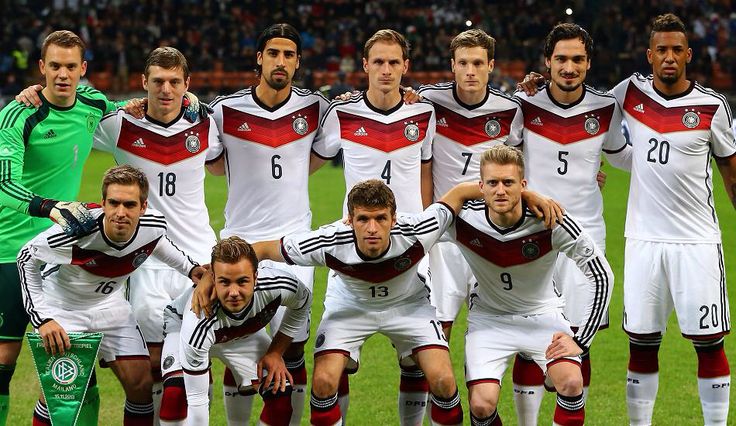 a group of soccer players pose for a team photo on the field in front of an audience