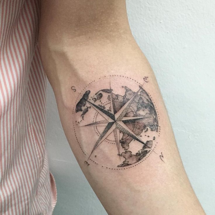 a man's arm with a compass tattoo on it