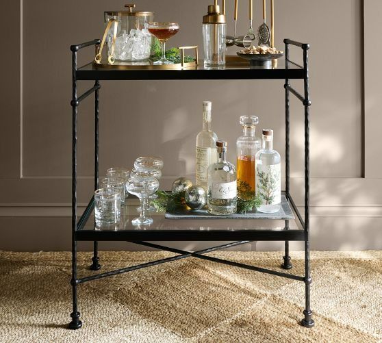 a bar cart filled with bottles and glasses on top of a carpeted floor next to a wall