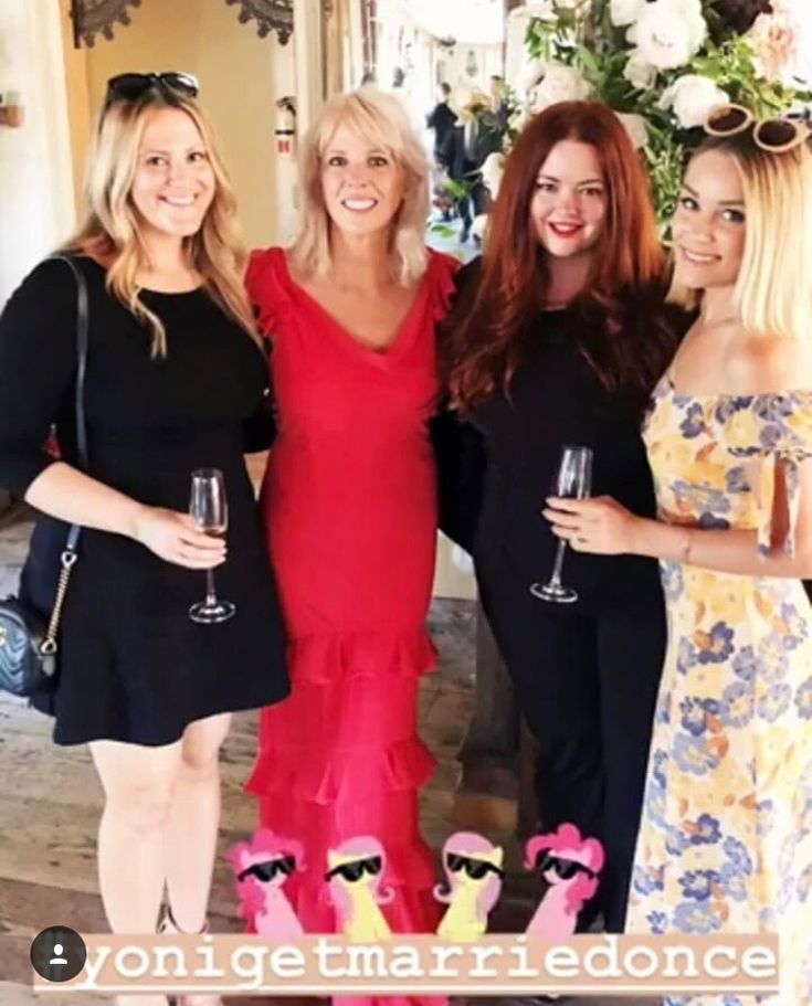 three women standing next to each other with wine glasses in their hands and one woman wearing a red dress