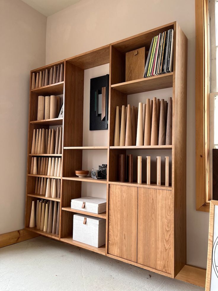 a bookshelf filled with lots of books next to a window in a room