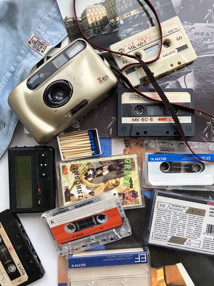 an old camera, cassettes, and other items are on the table next to each other