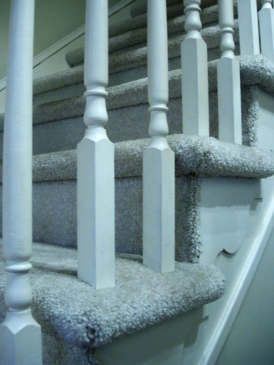 the carpeted stairs are lined with white balconies