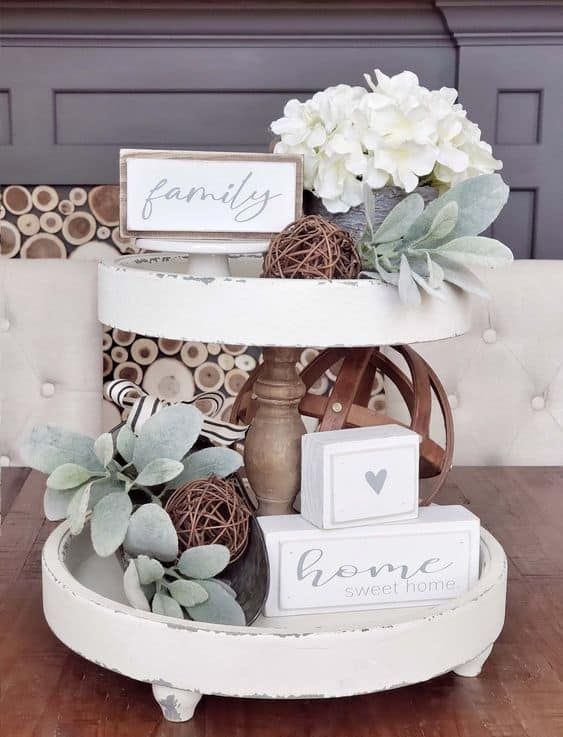 a three tiered cake stand with flowers on top and family signs above the tray