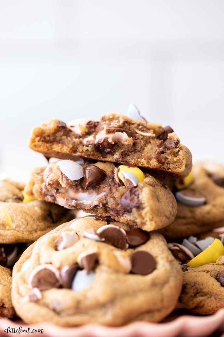 chocolate chip cookies stacked on top of each other in a pink bowl with white and yellow candies