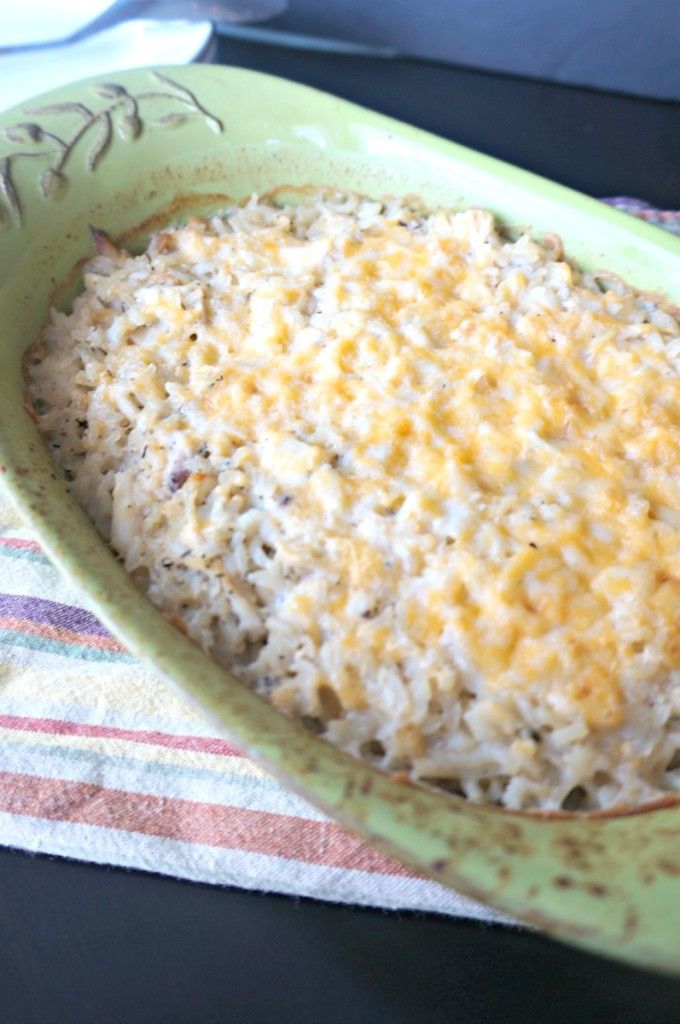 a green casserole dish filled with rice and cheese on a colorful towel next to a fork