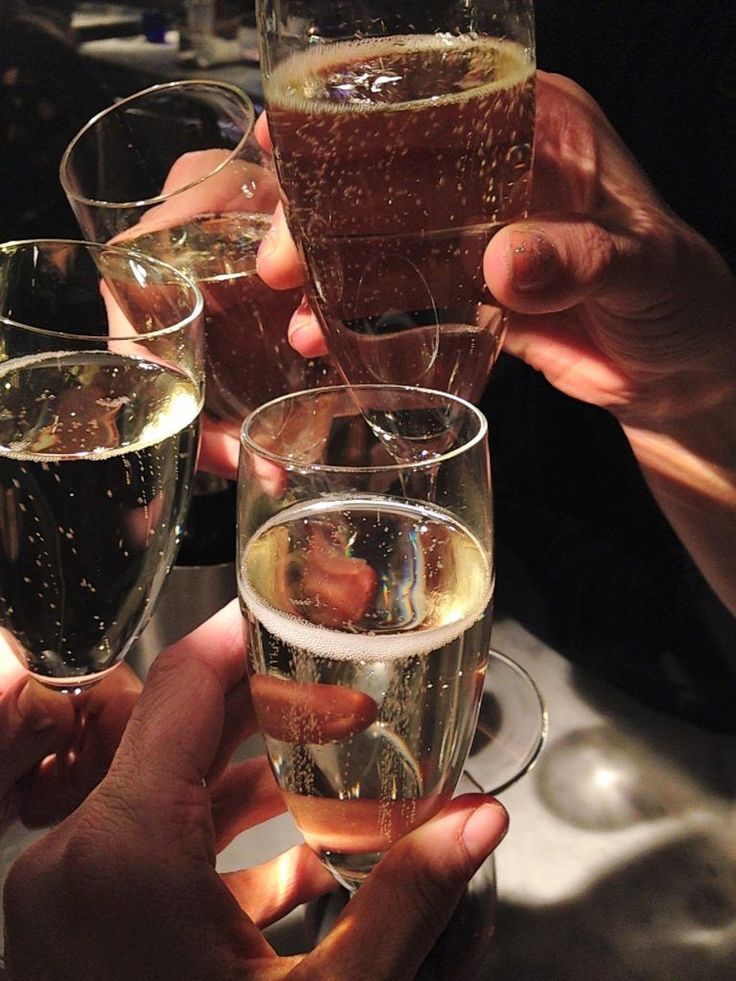 several people are holding up wine glasses with liquid in them and toasting at the same time