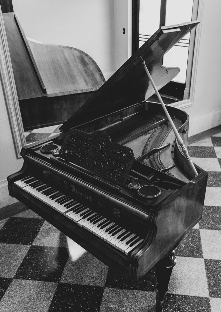 an old piano sitting on top of a checkered floor