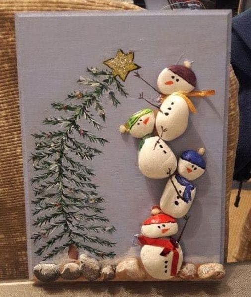 a group of snowmen standing next to a christmas tree on a wall with rocks