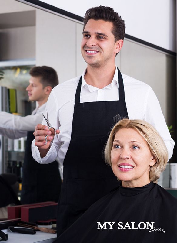 a man cutting a woman's hair with scissors in front of him at a salon