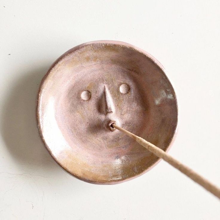 a brown plate with a face on it and a wooden stick sticking out of it