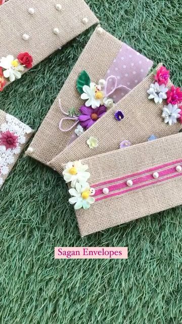 three pieces of fabric with flowers and pearls on them sitting in the grass next to each other