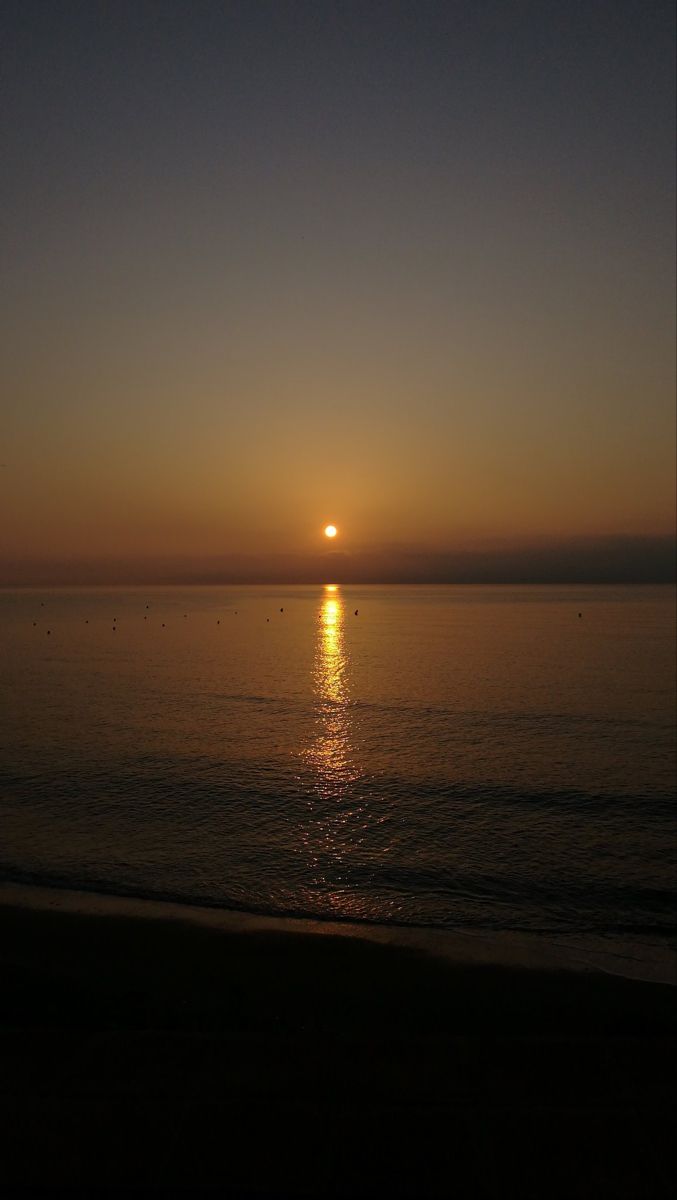 the sun is setting over the ocean on a clear day