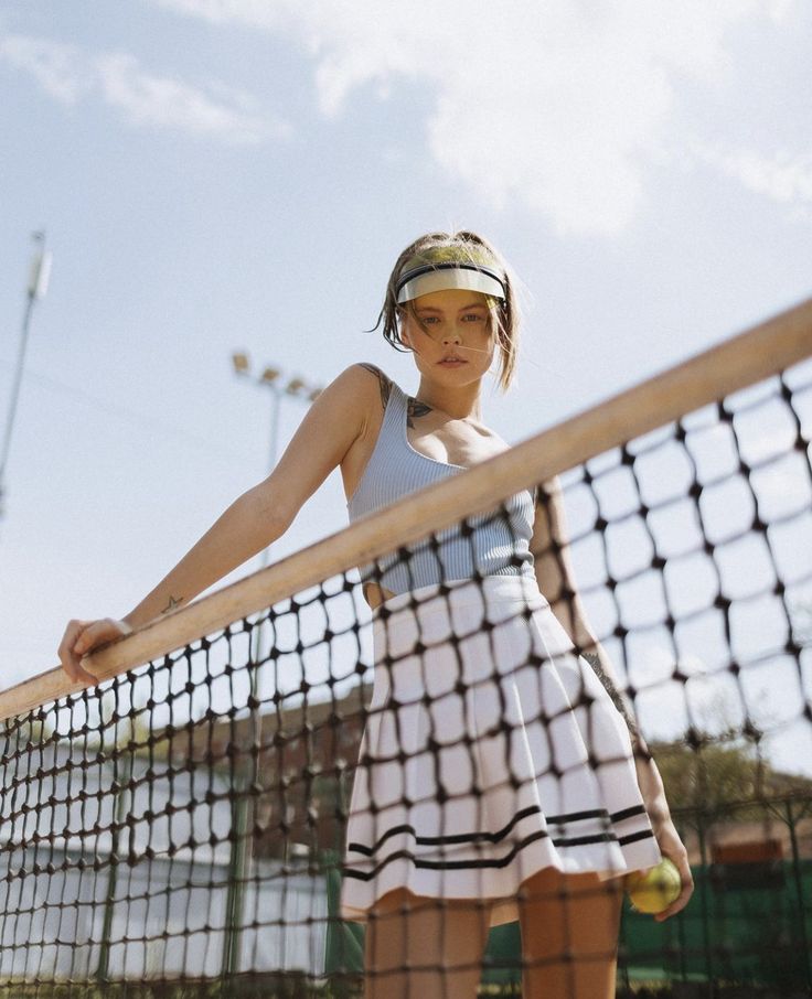 a young woman holding a tennis racquet on top of a tennis ball court