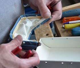 two hands are working on some tools in a box and another person is holding something