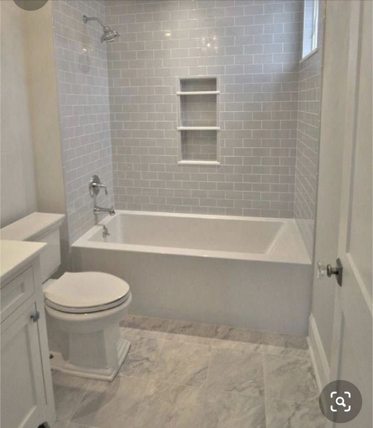 a white toilet sitting next to a bath tub in a bathroom under a chandelier