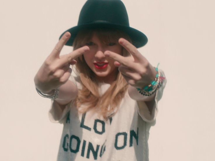 a woman wearing a hat making the vulcan sign