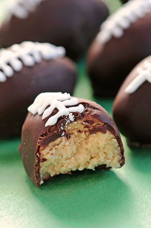 chocolate covered footballs with white frosting on green surface