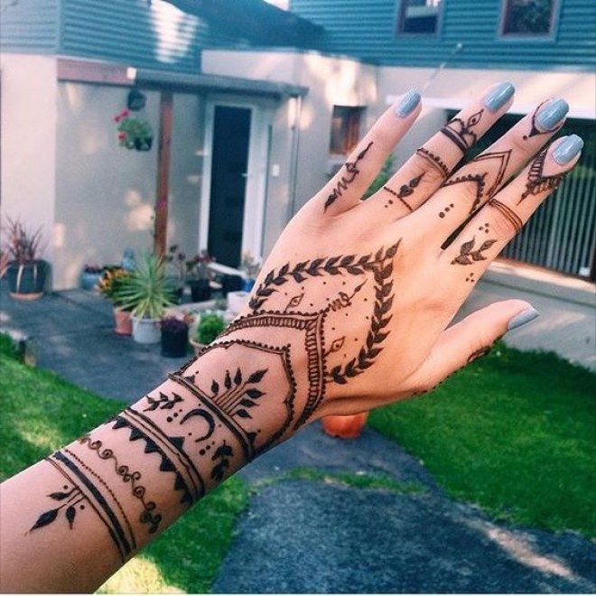 a woman's hand with hennap on it in front of a house