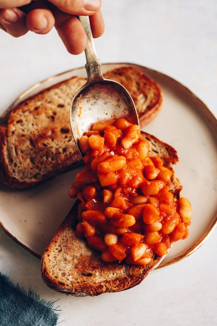 a person is spooning some beans out of a piece of bread on a plate