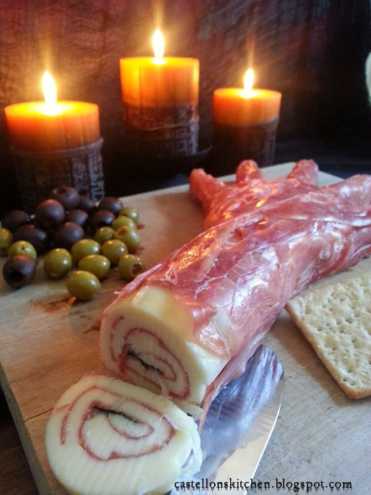 some food is laying out on a cutting board with candles and crackers in the background