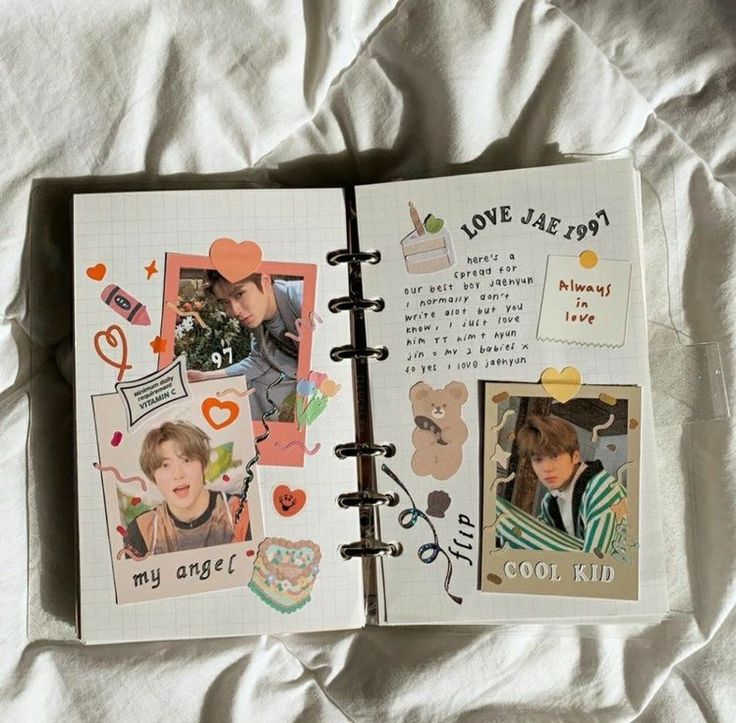 an open notebook with pictures and stickers on the pages is laying on a bed