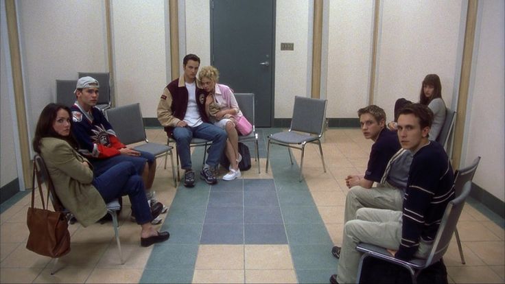 a group of people sitting around each other on chairs in a room with tile flooring