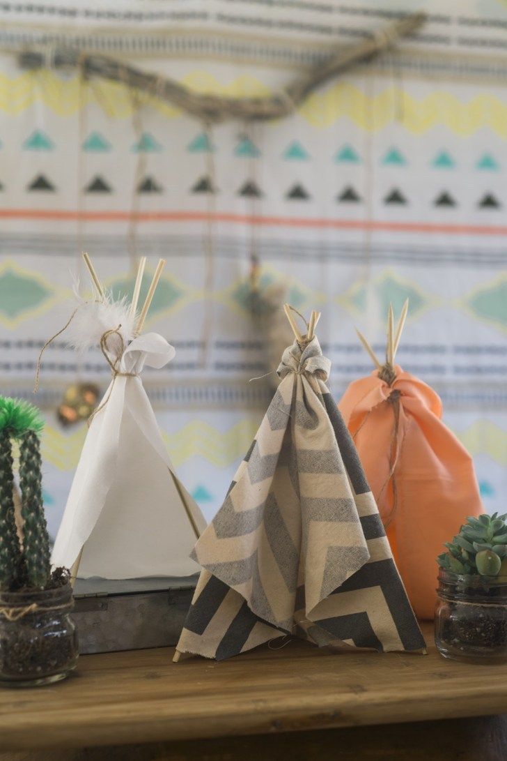 three teepees sitting on top of a wooden table next to cacti