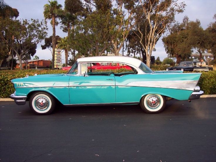 an old blue and white car parked in a parking lot