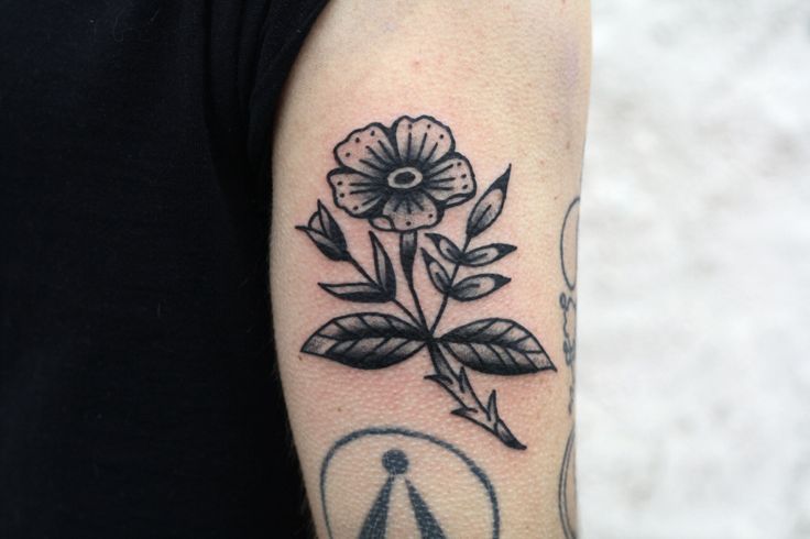 a black and white photo of a flower on the left arm, with an arrow in the middle