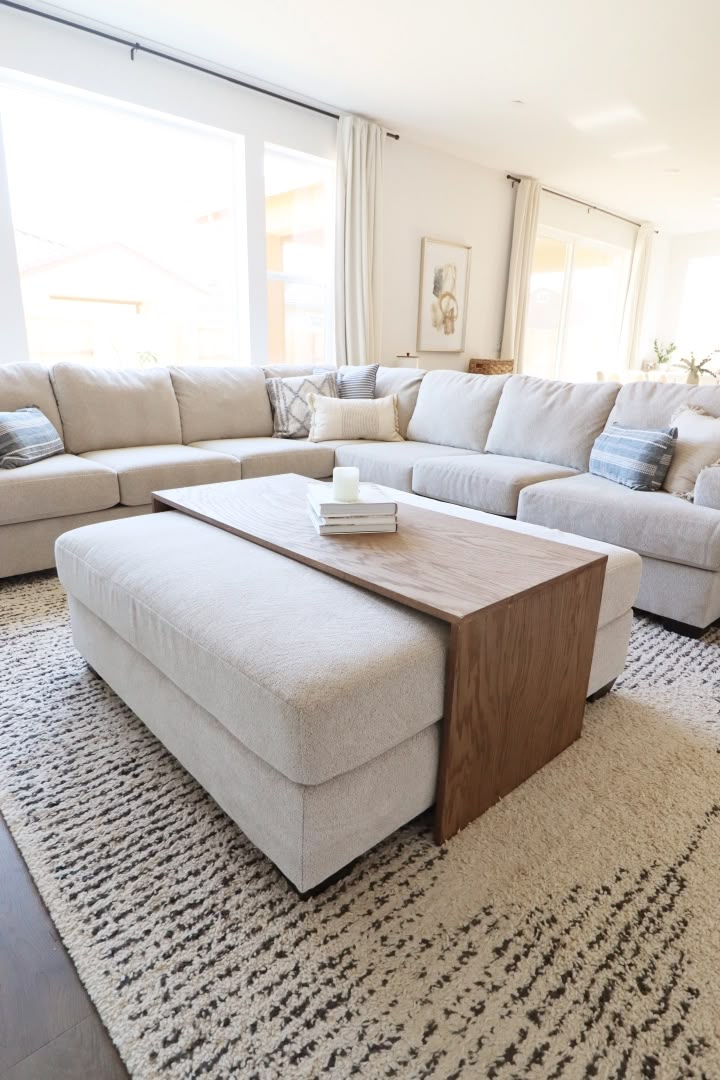 a living room with a large sectional couch and coffee table in front of the window