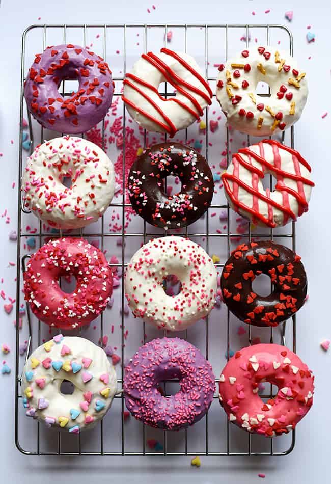 a bunch of doughnuts that are sitting on a cooling rack with sprinkles