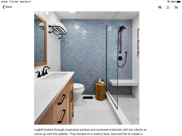 a modern bathroom with blue tile and wood accents on the walls, along with a walk in shower