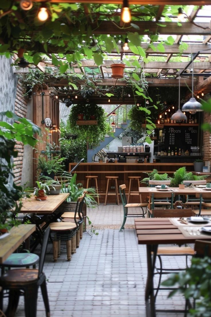 an outdoor dining area with tables and chairs, potted plants on either side of the bar